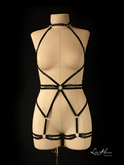 A black adjustable harness bodysuit on a mannequin, featuring a sleek choker neckline, silver garters, and bold double waist straps with twelve silver rings.