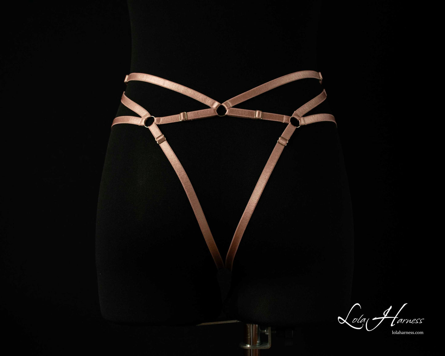 Close-up back bottom view of The Carry harness playsuit on a mannequin in dusty rose, focusing on the ouvert design.