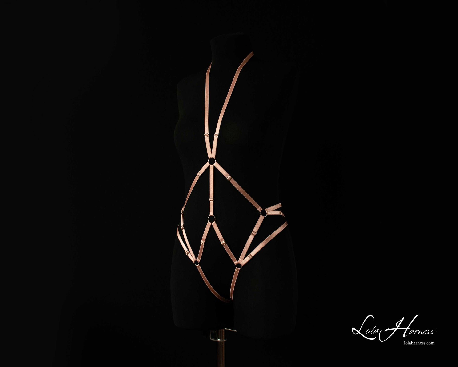 Side front view of The Carry harness playsuit on a mannequin in dusty rose, showing the strappy details.