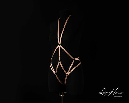 Side front view of The Carry harness playsuit on a mannequin in dusty rose, showing the strappy details.