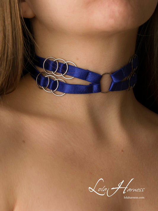Front view of The Grace harness choker in royal blue elastic, featuring adjustable straps and 12 rings, worn by a model.

